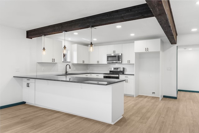 kitchen with hanging light fixtures, beam ceiling, kitchen peninsula, and appliances with stainless steel finishes