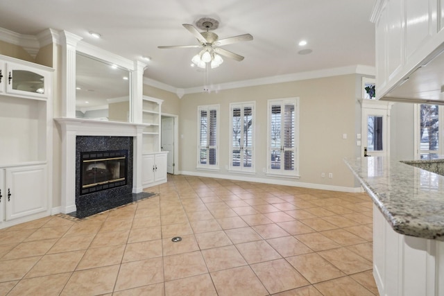 unfurnished living room featuring a premium fireplace, light tile patterned floors, crown molding, and a healthy amount of sunlight