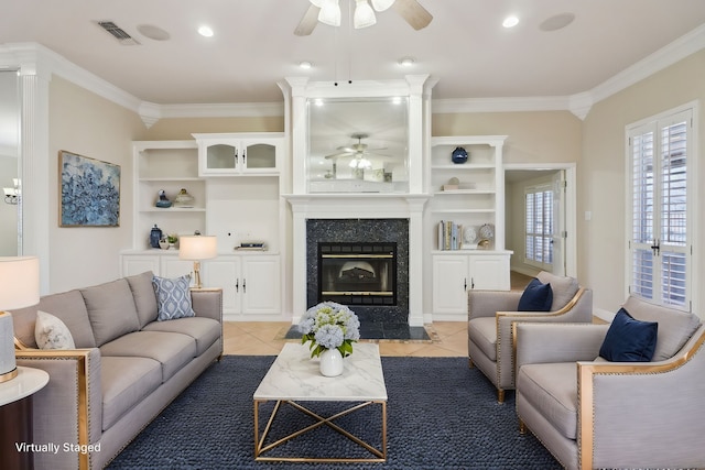 living room featuring ceiling fan, a high end fireplace, ornamental molding, and tile patterned flooring