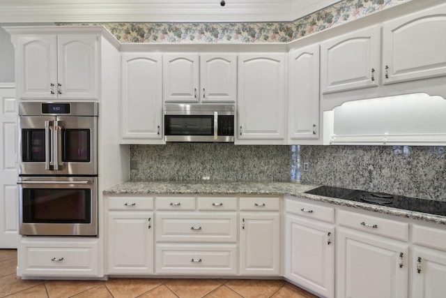 kitchen with light stone countertops, appliances with stainless steel finishes, and white cabinetry