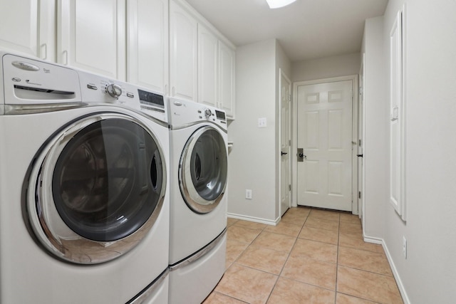 clothes washing area featuring washing machine and dryer, light tile patterned flooring, and cabinets