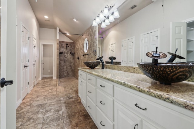 bathroom with vaulted ceiling, tiled shower, and vanity