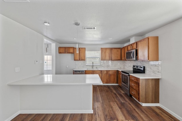 kitchen featuring appliances with stainless steel finishes, decorative light fixtures, dark wood-type flooring, decorative backsplash, and sink