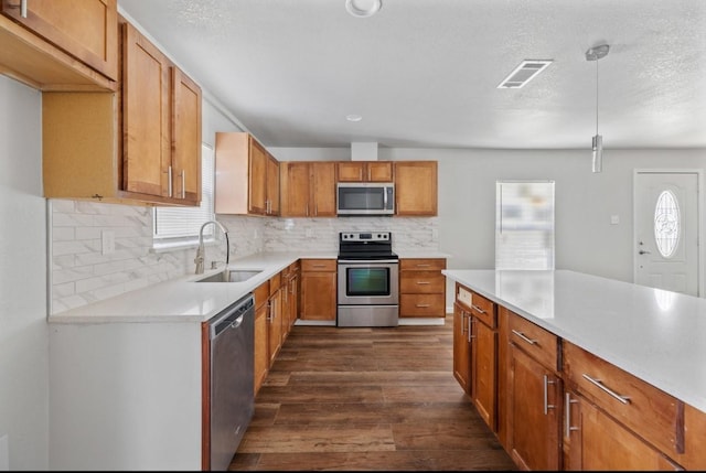 kitchen featuring a wealth of natural light, appliances with stainless steel finishes, decorative backsplash, sink, and hanging light fixtures