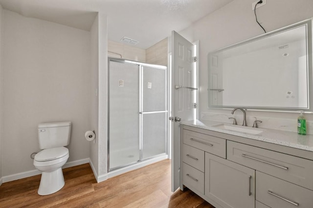 bathroom with hardwood / wood-style flooring, toilet, a shower with door, and vanity