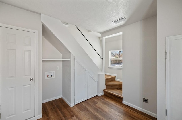 stairs with a textured ceiling and hardwood / wood-style floors