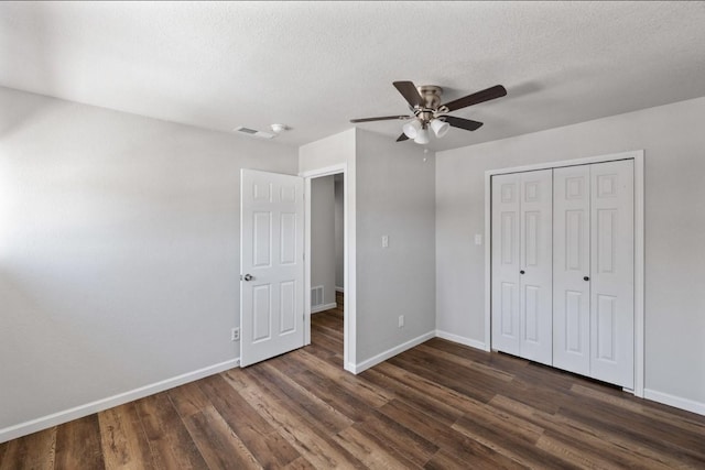 unfurnished bedroom with ceiling fan, a closet, dark wood-type flooring, and a textured ceiling