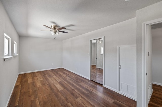 unfurnished bedroom with ceiling fan, dark wood-type flooring, and a textured ceiling