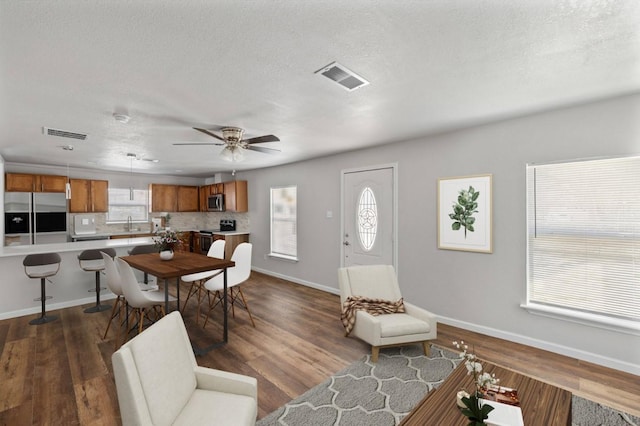 living room featuring ceiling fan, dark wood-type flooring, sink, and a textured ceiling