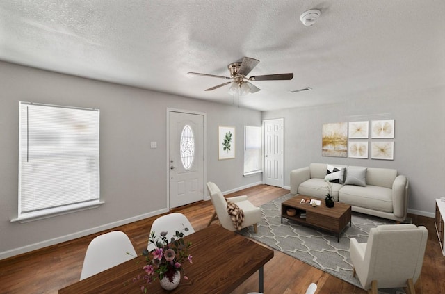 living room with hardwood / wood-style flooring, a textured ceiling, and ceiling fan