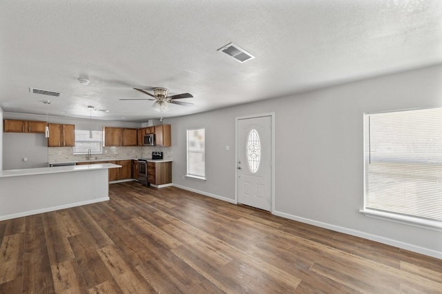 kitchen with ceiling fan, appliances with stainless steel finishes, backsplash, dark hardwood / wood-style floors, and decorative light fixtures