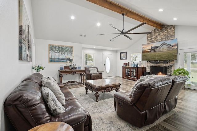 living room featuring a brick fireplace, ceiling fan, light hardwood / wood-style flooring, and lofted ceiling with beams