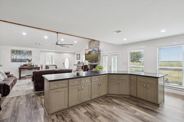 kitchen with hardwood / wood-style flooring, ceiling fan, a fireplace, vaulted ceiling, and a center island