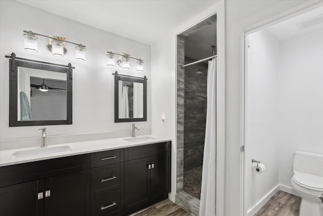 bathroom with toilet, vanity, a tile shower, and hardwood / wood-style floors