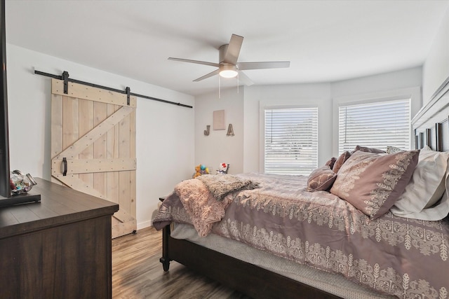 bedroom with ceiling fan, a barn door, and hardwood / wood-style floors