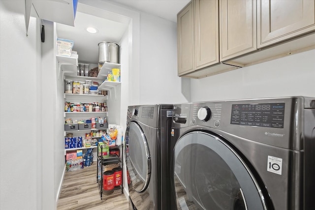 laundry room featuring light hardwood / wood-style flooring, independent washer and dryer, and cabinets