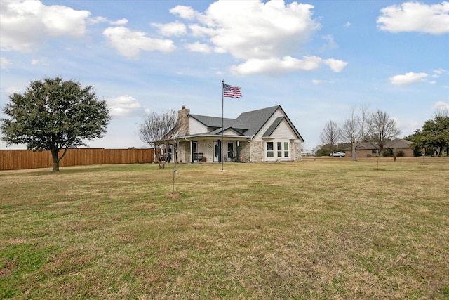 back of property with a yard, a chimney, fence, and a porch