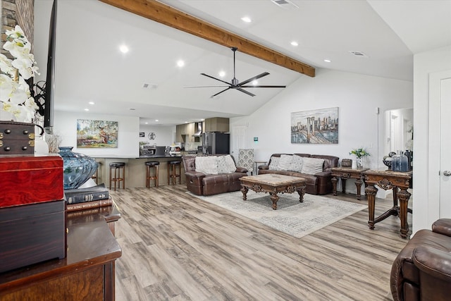 living area featuring lofted ceiling with beams, light wood finished floors, ceiling fan, and visible vents
