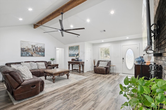 living room with ceiling fan, a brick fireplace, light hardwood / wood-style flooring, and lofted ceiling with beams