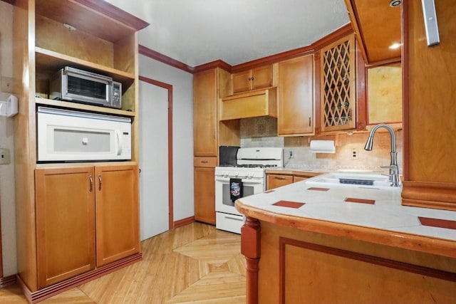 kitchen featuring ventilation hood, sink, ornamental molding, kitchen peninsula, and white appliances