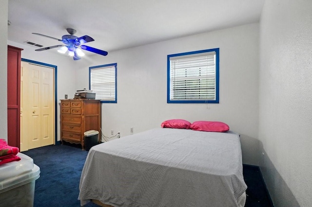 carpeted bedroom featuring multiple windows and ceiling fan