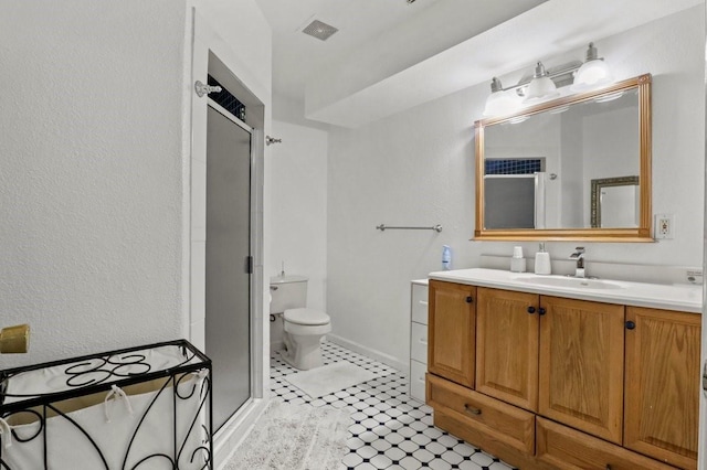 bathroom featuring walk in shower, vanity, toilet, and tile patterned flooring