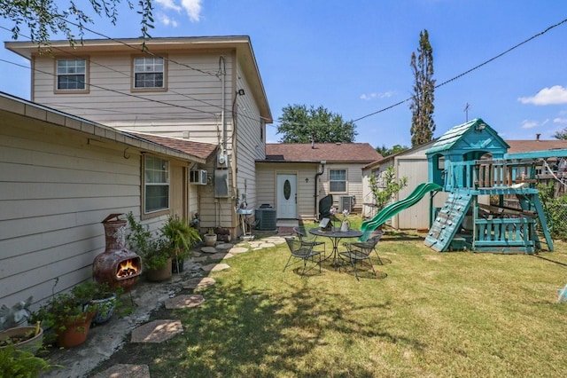 rear view of property featuring central AC, a yard, and a playground