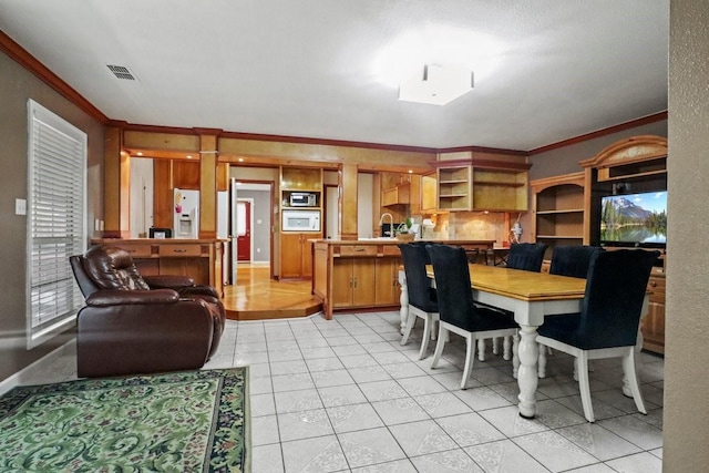 tiled dining room featuring sink and ornamental molding