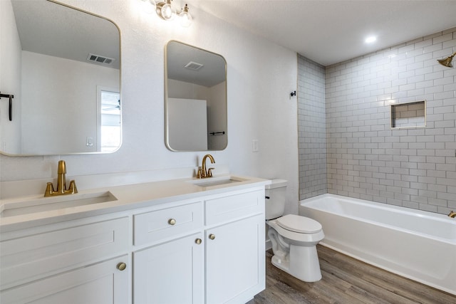 full bathroom featuring wood-type flooring, toilet, vanity, and tiled shower / bath