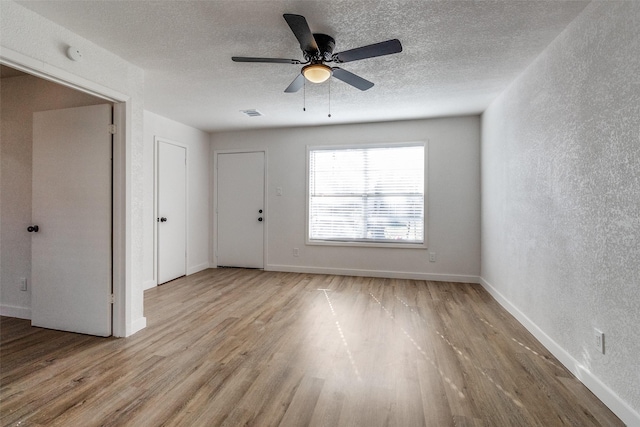 spare room featuring light wood-type flooring, ceiling fan, and a textured ceiling