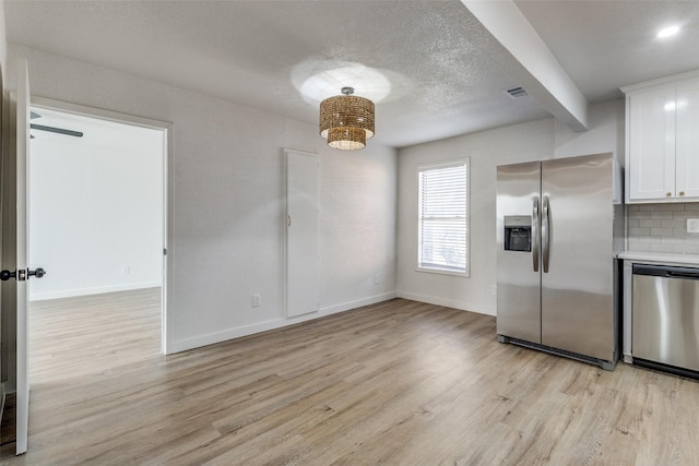 kitchen featuring stainless steel appliances, light hardwood / wood-style floors, backsplash, and white cabinetry