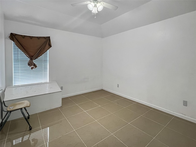 tiled empty room with ceiling fan and vaulted ceiling