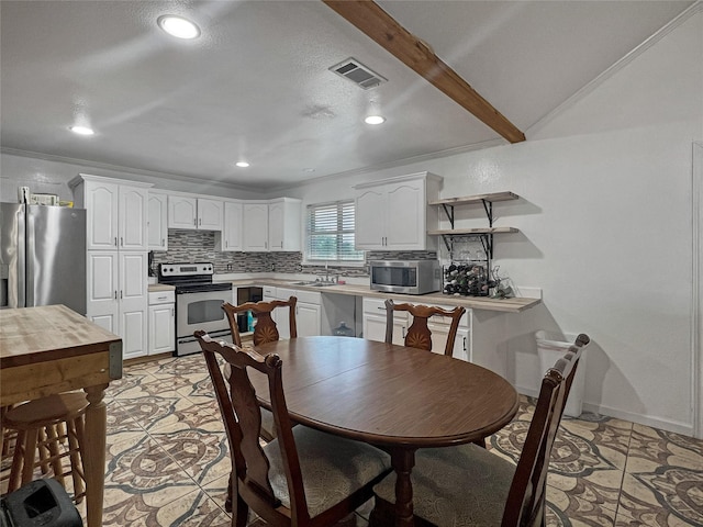 kitchen featuring white cabinetry, stainless steel appliances, beamed ceiling, and tasteful backsplash