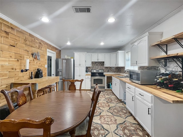 dining room with sink, ornamental molding, and light tile patterned flooring