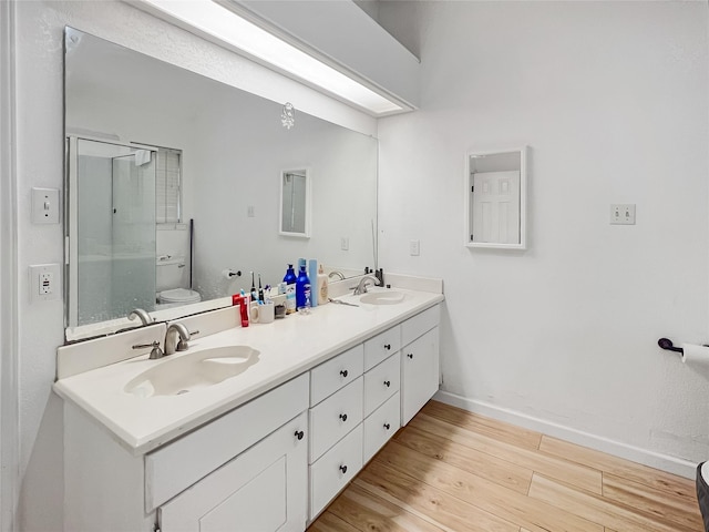 bathroom with hardwood / wood-style floors, toilet, vanity, and an enclosed shower