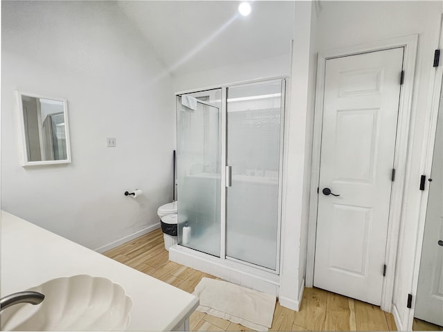 bathroom featuring toilet, vanity, vaulted ceiling, hardwood / wood-style flooring, and a shower with shower door