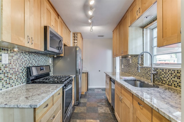 kitchen with appliances with stainless steel finishes, sink, backsplash, rail lighting, and light stone counters