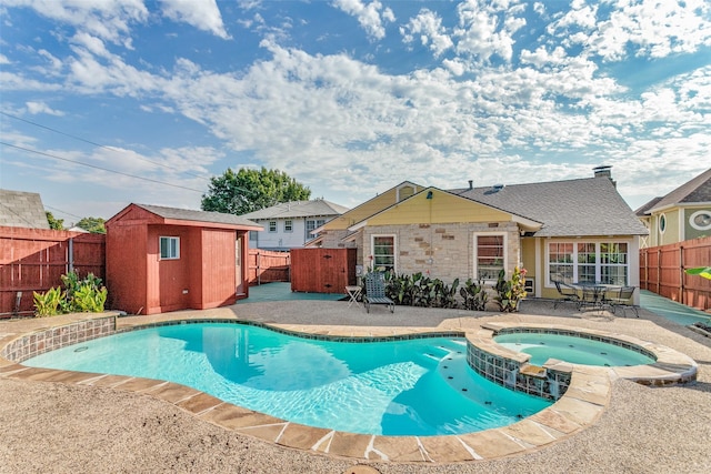 view of swimming pool with a shed, an in ground hot tub, and a patio