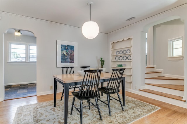 dining space featuring built in features, crown molding, and hardwood / wood-style floors