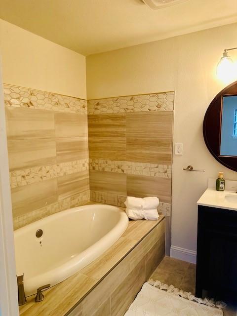 bathroom with vanity, tile patterned floors, and tiled bath