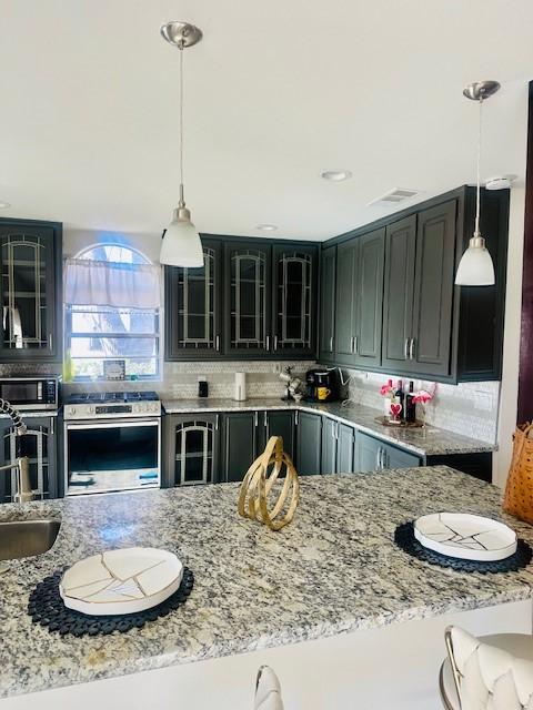 kitchen featuring hanging light fixtures, decorative backsplash, sink, and appliances with stainless steel finishes