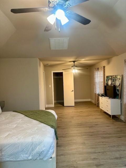 bedroom with hardwood / wood-style floors, vaulted ceiling, a closet, and ceiling fan