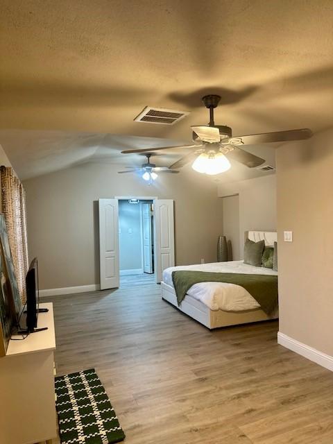 bedroom with wood-type flooring, ceiling fan, and vaulted ceiling