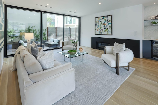 living room with wine cooler, a wall of windows, bar, and light hardwood / wood-style floors