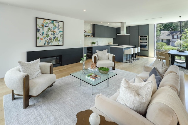 living room featuring sink, light wood-type flooring, beverage cooler, and floor to ceiling windows