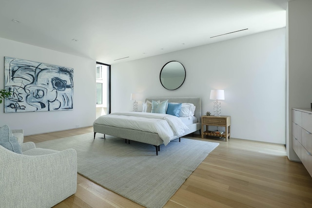 bedroom featuring a wall of windows and light hardwood / wood-style floors