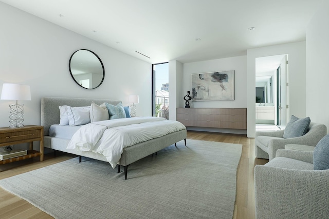 bedroom with ensuite bath and light hardwood / wood-style floors