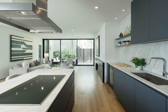 kitchen featuring light hardwood / wood-style floors, floor to ceiling windows, black electric cooktop, light stone countertops, and sink