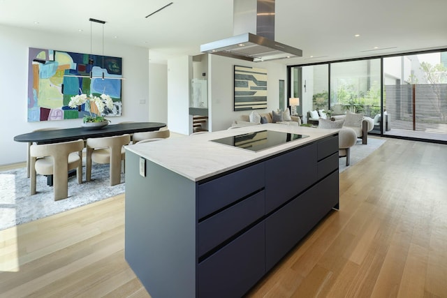 kitchen featuring a kitchen island, decorative light fixtures, island range hood, light wood-type flooring, and expansive windows