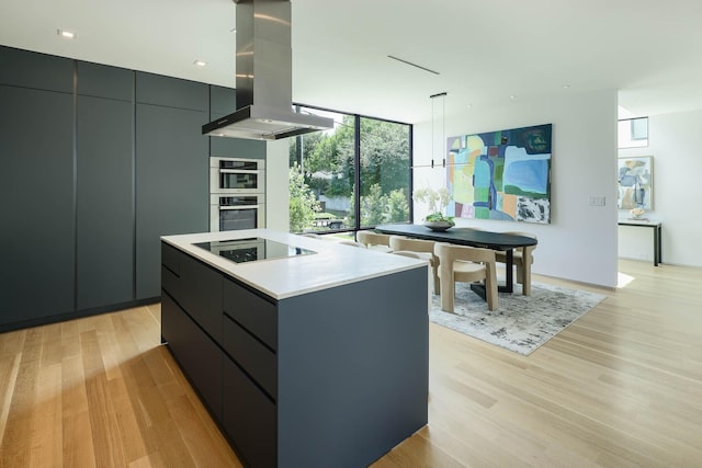 kitchen featuring a center island, island exhaust hood, hanging light fixtures, floor to ceiling windows, and black electric cooktop